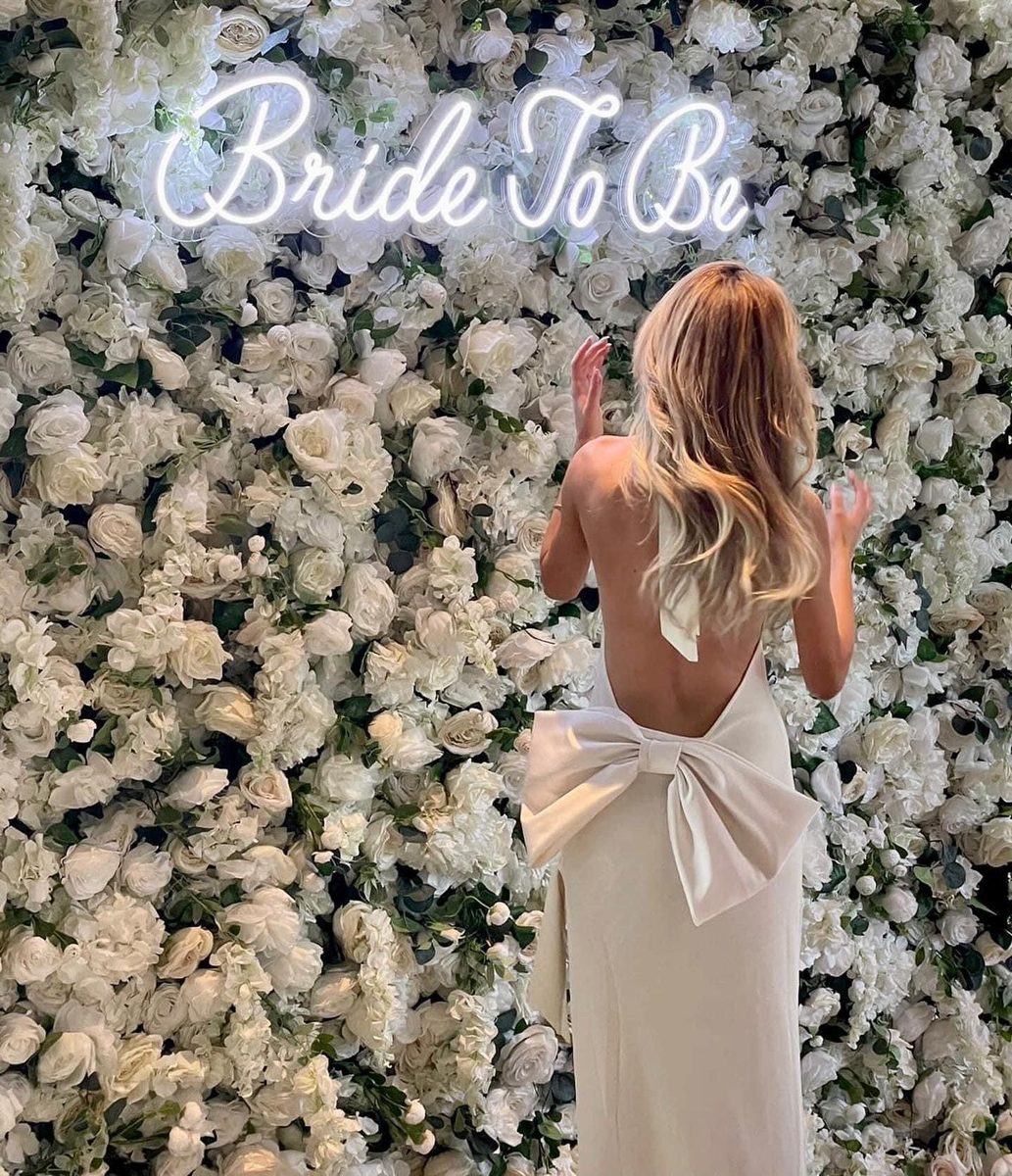 Floral flower wall with a Bride To Be neon sign at an event